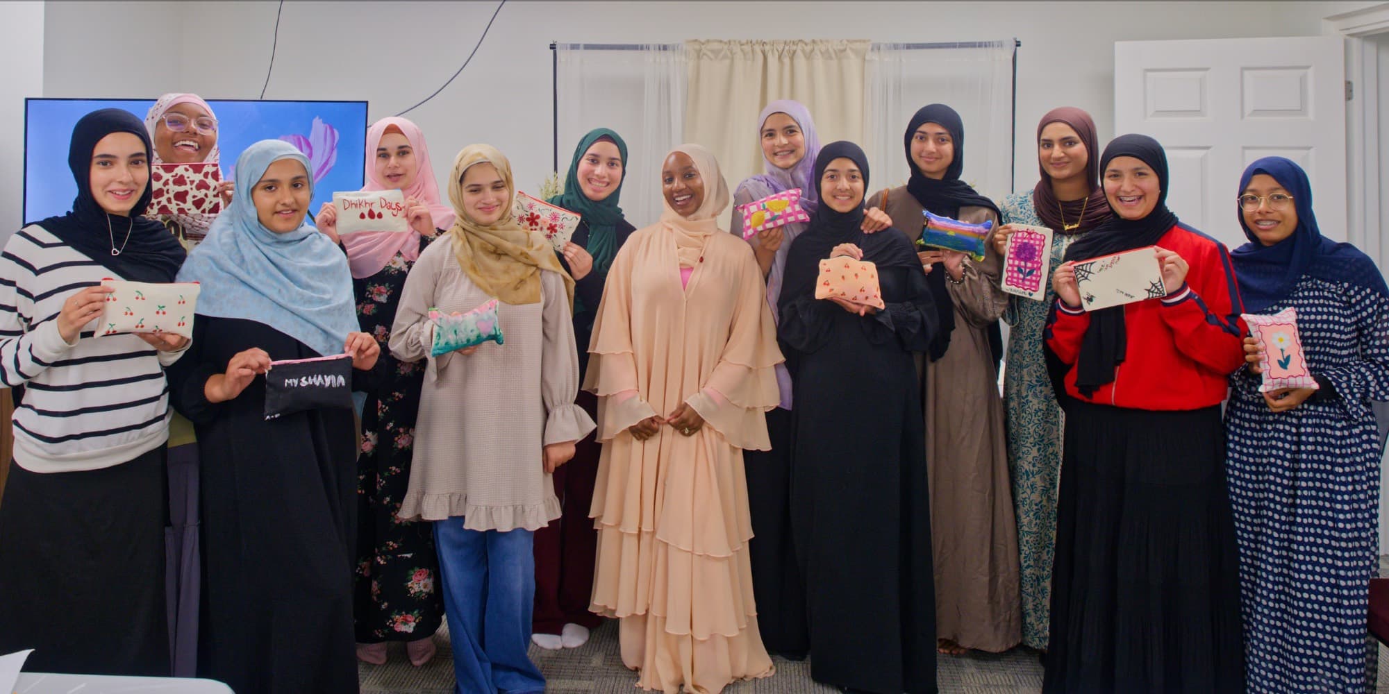 Group photo of everyone who attended the Teen Talk seminar, holding the pouches they painted