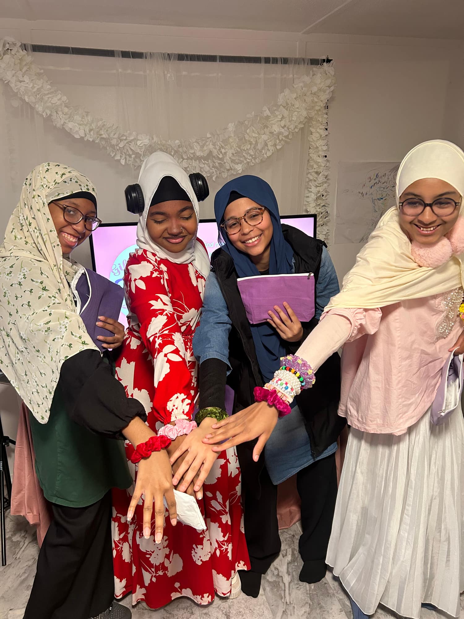 Four teens laughing together with their hands joined in the middle
